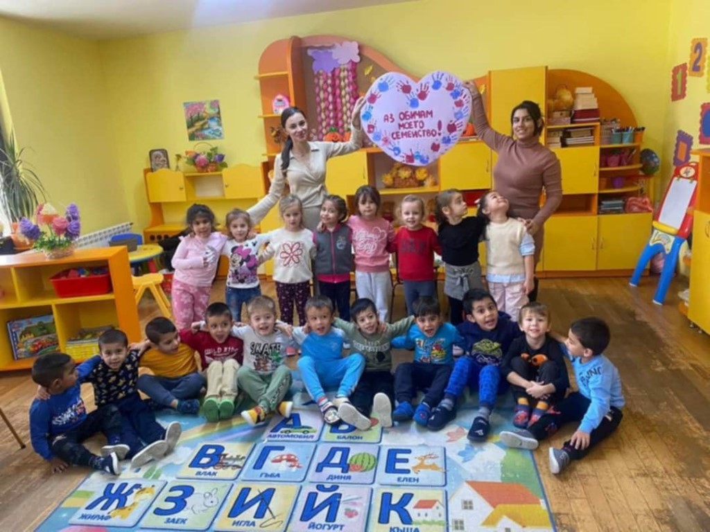 Деца и възрастни с детска табела в класна стая.