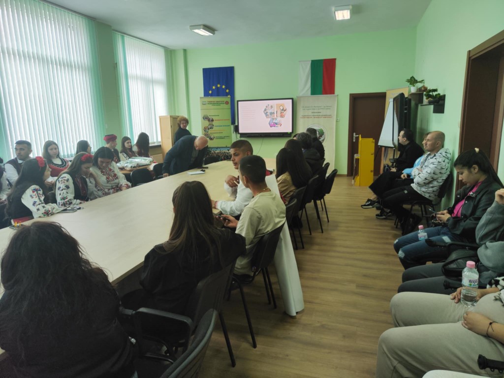 Група хора седят в зала за срещи.