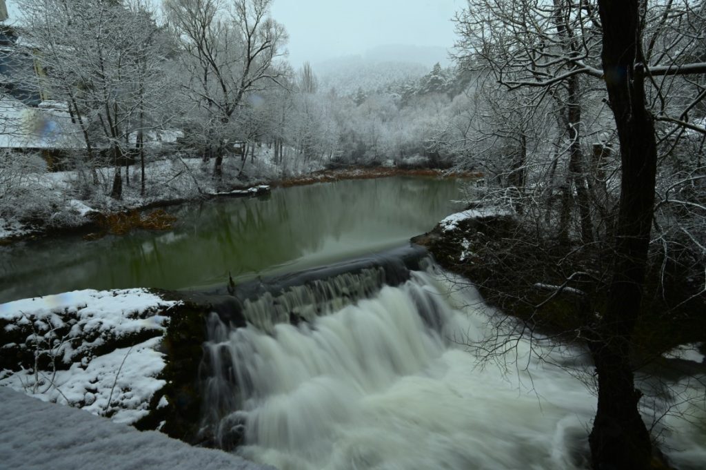 Заснежен водопад в спокойна река.