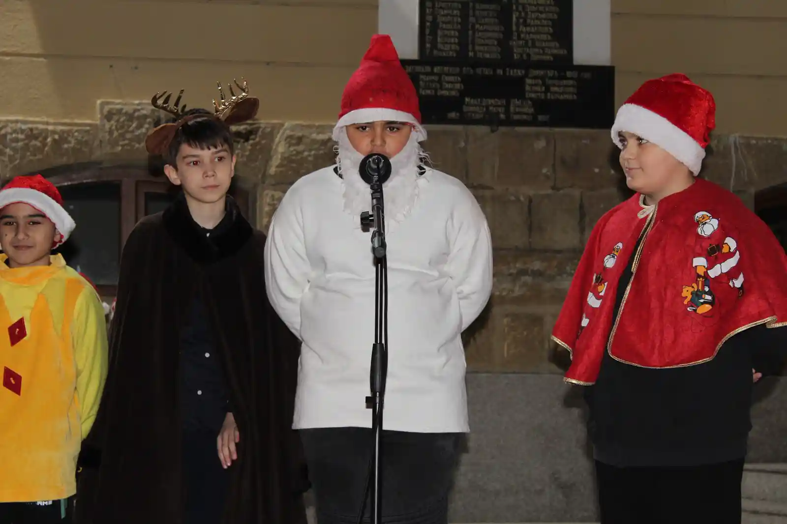 Деца с коледни костюми на сцена.