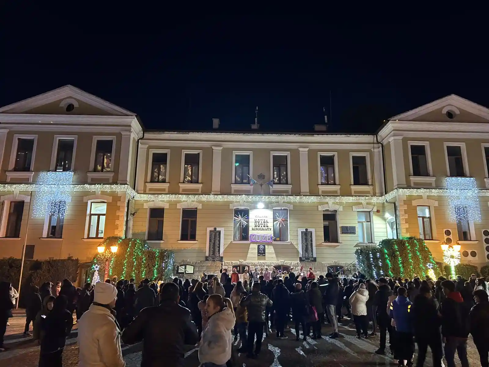 Хора събрани пред сградата на общината в Котел, украсена за коледа.