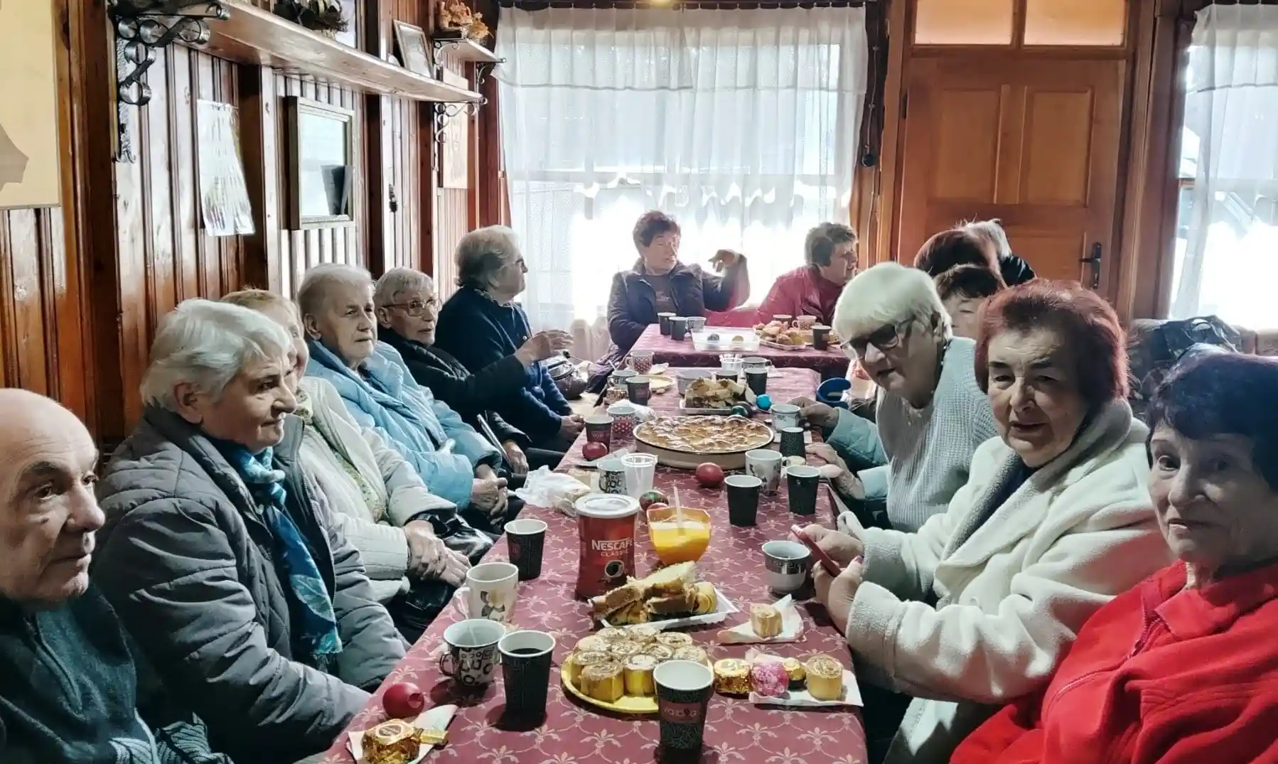 Група хора на маса, заобиколена от вкусни ястия и напитки, наслаждавайки се на компанията си.