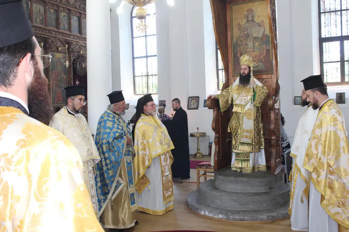 Духовници на църковна служба, облечени в традиционни одежди, в храм с богата икона.