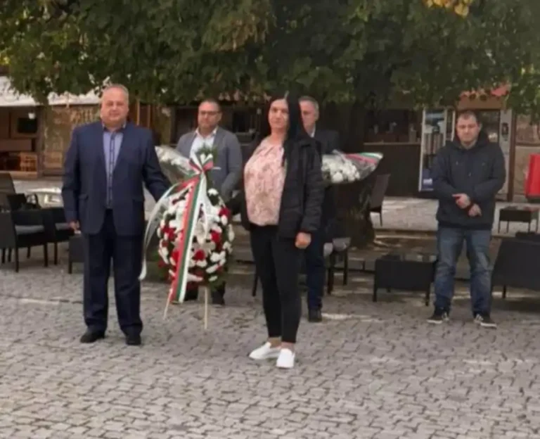 Членове на обществото полагат венец в памет на важна историческа дата, събрани на открито.
