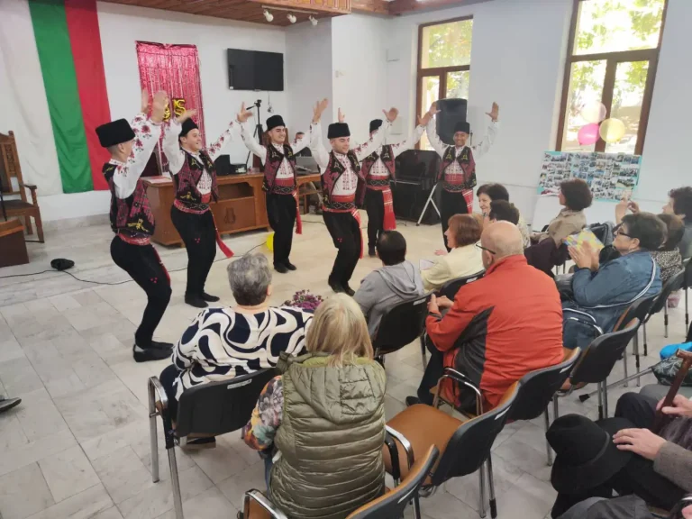 Танцьори в традиционни костюми изпълняват народни танци пред публика на събитие.